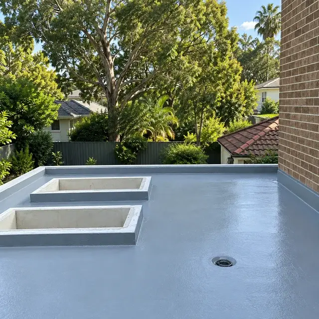 Grey waterproofing membrane across a residential terrace with sealed upstands and drainage